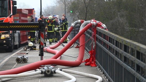 Schläuche der Feuerwehr hängen in Hamburg-Rothenburgsort über ein Brückengeländer. © picture alliance/dpa Foto: Jonas Walzberg