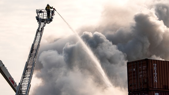 Feuerwehrleute löschen im Stadtteil Harburg einen brennenden Schrotthaufen. © dpa Foto: Daniel Bockwoldt
