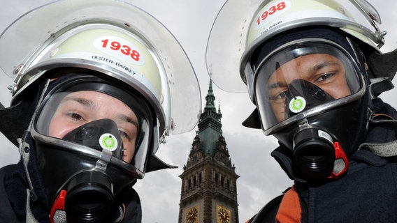 Zwei Feuerwehrleute zeigen in Hamburg beim Katastrophenschutz-Tag ihre Schutzausrüstung. © dpa Foto: Angelika Warmuth