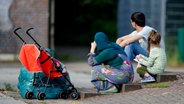 Flüchtlinge sitzen in Hamburg auf dem Hof einer ehemaligen Schule. © dpa-Bildfunk Foto: Daniel Bockwoldt