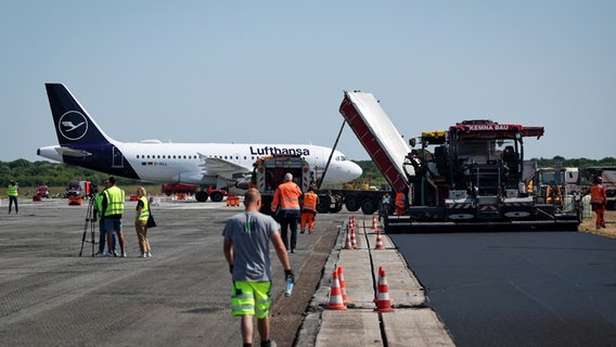 Arbeiter am Hamburger Flughafen. Für Erneuerungsarbeiten ist eine Start- und Landebahn gesperrt. © picture alliance/dpa Foto: Christian Charisius