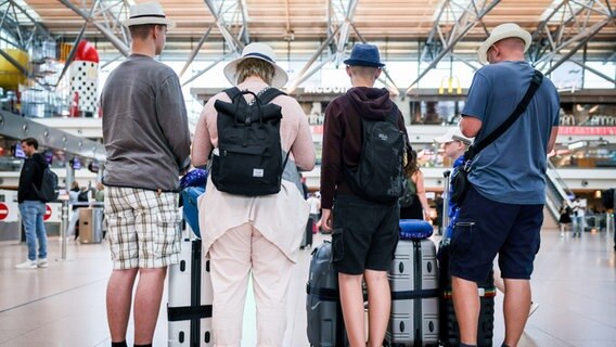 Eine Familie steht im Terminal 1 am Flughafen auf dem Weg in den Urlaub. © picture alliance/dpa | Christian Charisius Foto: Christian Charisius