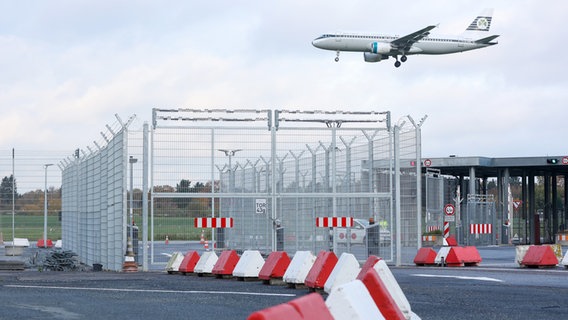 Das Tor auf das Vorfeld des Hamburger Flughafens ist geschlossen, eine Maschine der Fluggesellschaft Aer Lingus setzt zur Landung an. © dpa Foto: Bodo Marks