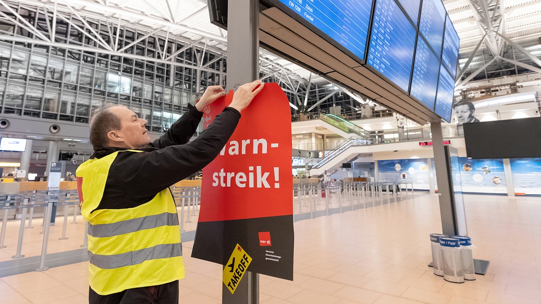 Ein Verdi-Vertreter hängt ein Plakat mit der Aufschrift «Warnstreik» in einem Terminal im Hamburger Flughafen auf. 