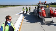 Mitarbeiter des Wartungs- und Instandhaltungsteams erneuern die Markierungen auf einer der beiden Start- und Landebahnen am Hamburger Flughafen. © picture alliance/dpa Foto: Christian Charisius