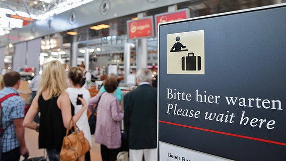 Ein Schild mit der Aufschrift "Bitte hier warten" vor dem Check-In © dpa-Bildfunk 