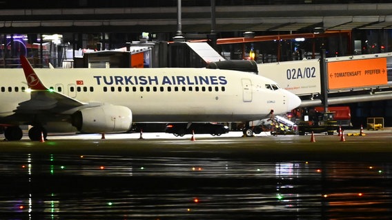 Ein dunkelfarbiges Auto steht am Flughafen unter einem Flieger von Turkish Airlines. Der Hamburger Flughafen ist nach dem Eindringen eines Fahrzeugs auf das Gelände gesperrt worden. © picture alliance / dpa Foto: Jonas Walzberg