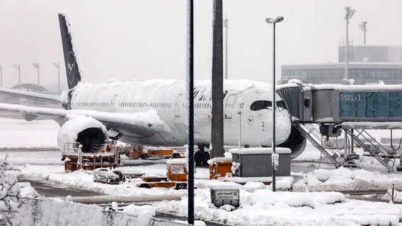 Eine Maschine der Lufthansa steht auf dem verschneiten Flughafen in München. © Karl-Josef Hildenbrand/dpa 