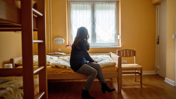 Eine Frau sitzt im Frauenhaus auf einem Bett © dpa / picture alliance Foto: Maja Hitij