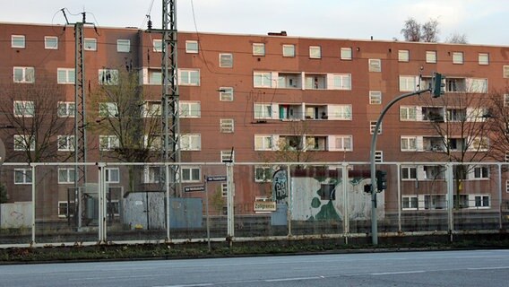 Ein Wohnblock auf der Veddel steht hinter dem Freihafenzaun mit der Aufschrift "Zollgrenze". © NDR Foto: Daniel Sprenger