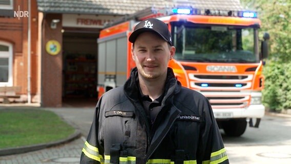 Ein junger Mann in Feuerwehr-Uniform lächelt in die Kamera. © NDR Foto: Anna Leusch