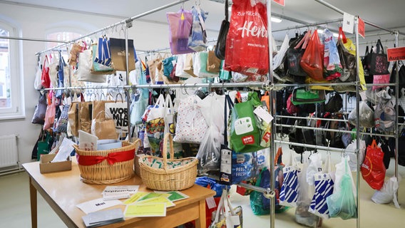 Plastiktüten und Taschen hängen an Stellwänden bei der Einweihung des neuen Fundbüros in Hamburg. © picture alliance / dpa Foto: Christian Charisius