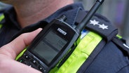 Ein Polizist in Hamburg hält ein Funkgerät in der Hand. © picture alliance/dpa Foto: Marcus Brandt