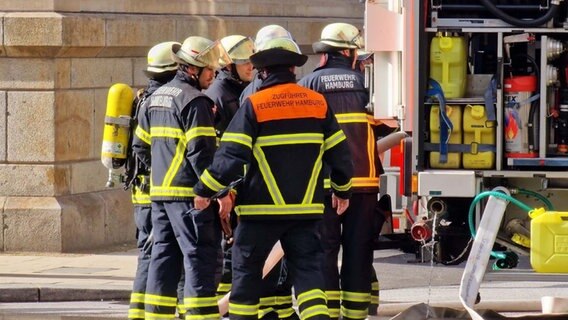 Feuerwehrleute stehen an einem Einsatzfahrzeug. © HamburgNews Foto: Christoph Seemann
