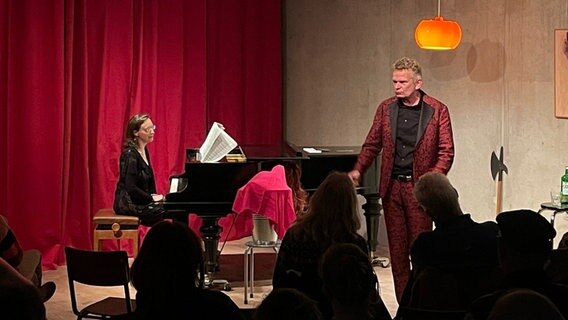 Eine Frau sitzt auf einer Bühne am Klavier, ein Mann steht daneben und singt. © NDR Foto: Annete Matz