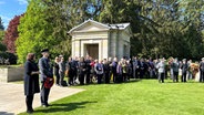 Mehrere Teilnehmer bei der zentralen Gedenkveranstaltung zum Ende des Zweiten Weltkriegs vor 80 Jahren auf dem Ohlsdorfer Friedhof in Hamburg. © NDR Foto: Anna-Lena Ehle