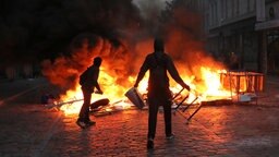 Zwei Randalierer stehen im Schanzenviertel vor einer brennenden Barrikade. © dpa 