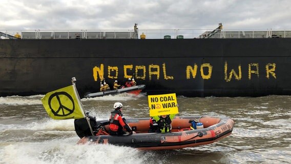Aktivisten von Greenpeace haben den Kohlefrachter "Grand T", der mit russischer Kohle beladen auf dem Weg in den Hamburger Hafen ist, mit dem Schriftzug "No coal no war" (keine Kohle, kein Krieg) versehen und fahren mit einem Schlauchboot neben dem Schiff. © picture alliance/dpa | Daniel Bockwoldt Foto: Daniel Bockwoldt