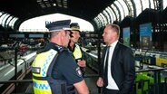 Hamburgs Innensenator Andy Grote (SPD) spricht im Hauptbahnhof mit Einsatzleitern der Polizei. © Jonas Walzberg/dpa 