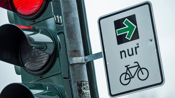 An einer Ampel einer Kreuzung hängt ein grüner Pfeil, der es Fahrradfahrern erlaubt, rechts abzubiegen wenn die Ampel rot ist. © picture alliance / dpa Foto: Christophe Gateau