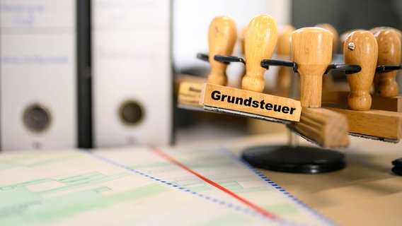Ein Stempel mit der Aufschrift "Grundsteuer" auf einem Schreibtisch. © IMAGO / Lobeca 