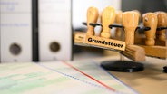Ein Stempel mit der Aufschrift "Grundsteuer" auf einem Schreibtisch. © IMAGO / Lobeca 