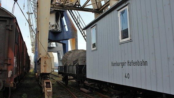 Ein Waggon der Hafenbahn steht im historischen Teil des Hamburger Hafens auf dem Kleinen Grasbrook unter Kränen. © NDR Foto: Daniel Sprenger