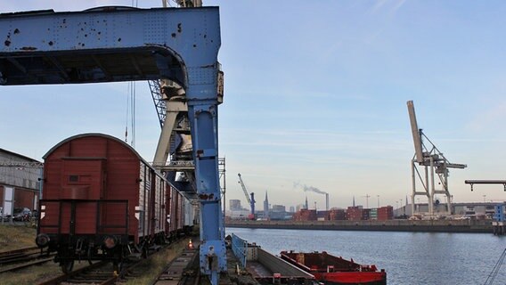 Ein alter Kran steht im historischen Teil des Hamburger Hafens auf dem Kleinen Grasbrook, im Hintergrund ist eine moderne Containerbrücke zu erkennen. © NDR Foto: Daniel Sprenger