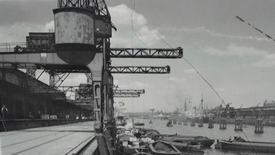 Historisches Bild vom Hamburger Hafen, Kräne stehen am Kai, vor dem Boote anlegen. © Hamburger Hafenmuseum 