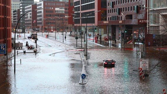 Ein Fahrzeug steckt auf der überschwemmten Straße Am Sandtorkai in der Hamburger Hafencity fest. © Christian Charisius/dpa Foto: Christian Charisius