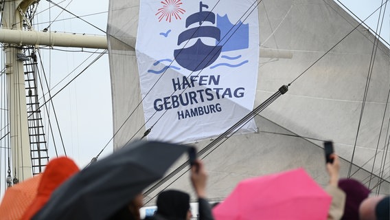 Am 5. Mai 2023 steht auf einem Plakat an dem Segel der "Rickmer Rickmers" steht "Hafen Geburtstag Hamburg" © picture alliance/dpa | Jonas Walzberg Foto: Jonas Walzberg