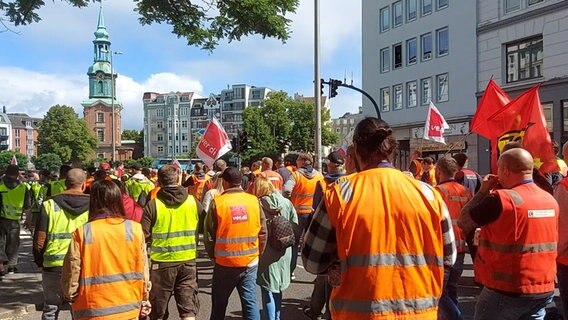 Mehrere Hafenarbeiterinnen und Hafenarbeiter laufen bei einem Warnstreik durch die Hamburger Innenstadt. © NDR 