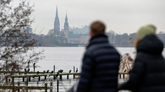 Spaziergänger in Hamburg mit dem Stadtpanorama mit St. Nikolai-Kirche, Rathaus und Elbphilharmonie im Hintergrund © dpa Foto: Jonas Walzberg