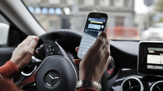 Ein Autofahrer hält ein Handy in der Hand. © picture-alliance / dpa Foto: Sami Halinen