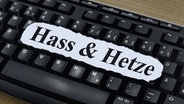 Die Worte Hass und Hetze liegen ausgedruckt auf einer Computertastatur. © ZB Foto: Sascha Steinach