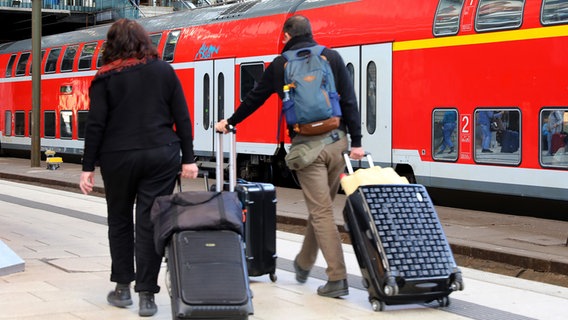 Eine Frau und ein Mann gehen mit Koffern über einen Bahnsteig am Hamburger Hauptbahnhof. © pressefoto_korb Foto: Micha Korb