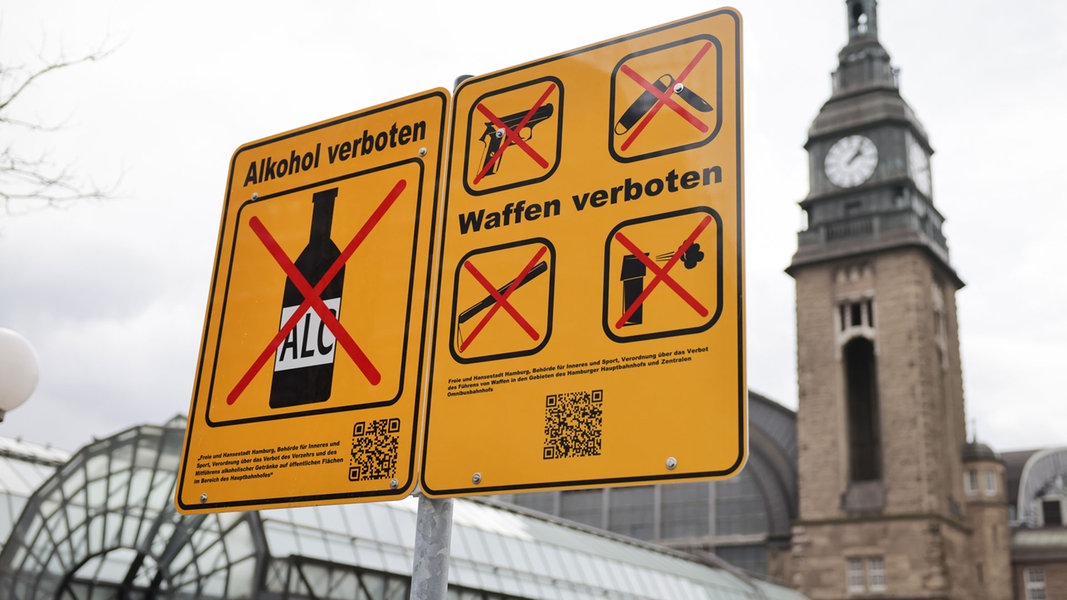 Ein neues Hinweisschild zum Verbot von Alkoholkonsum ist neben einem Verbotsschild für Waffen am Hachmannplatz vor dem Hauptbahnhof zu sehen. 
