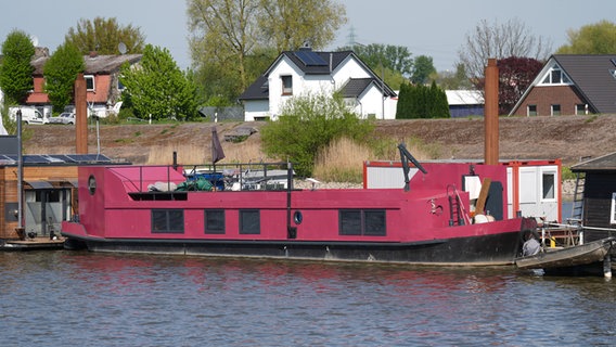 Das pink-farbene Hausboot, in dem eine 58 Jahre alte Frau tot aufgefunden worden war, liegt an einem Steg im Holzhafen im Hamburger Stadtteil Moorfleet. © picture alliance / dpa Foto: Marcus Brandt