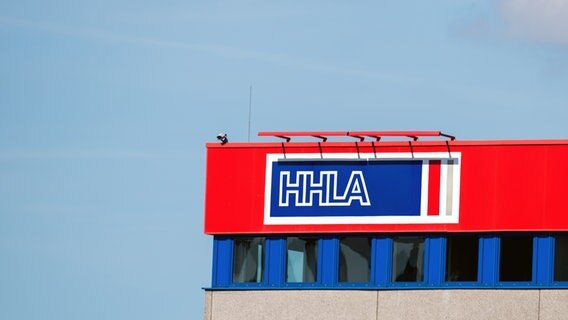 The logo of Hamburger Hafen und Logistik AG (HHLA) on a building in the port of Hamburg.  © picture alliance Photo: Daniel Reinhardt