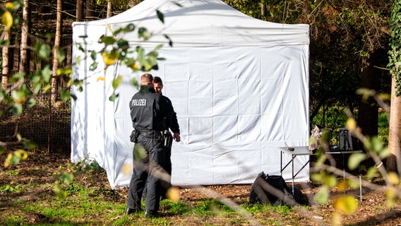 Polizeibeamte stehen vor einem Zelt im Altonaer Volkspark, wo auf dem Gelände eines Kleingartens nach Spuren zu dem seit 1999 vermissten Mädchen Hilal gesucht wird. © Daniel Bockwoldt/dpa 