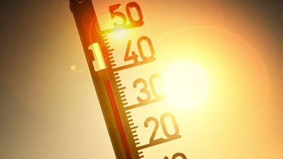 Ein Thermometer vor einer Sonne zeigt hohe Temperaturen an. © picture alliance / Chromorange 