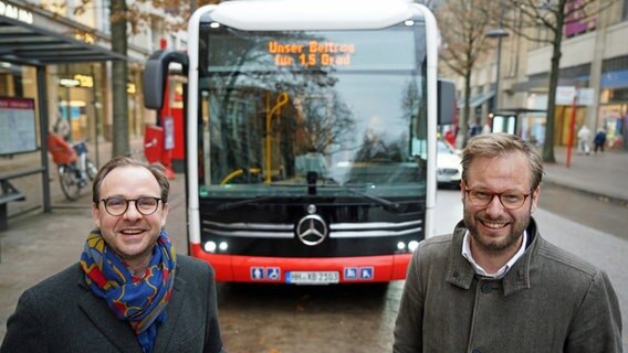 Verkehrssenator Anjes Tjarks (r.) und Henrik Falk, Vorstandsvorsitzender der Hochbahn, stehen vor dem 100. Elektrobus, der in Hamburg in Betrieb genommen wird. © picture alliance / dpa Foto: Marcus Brandt
