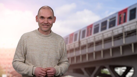 Ole Wackermann steht vor einem Foto einer Hochbahn. © NDR 