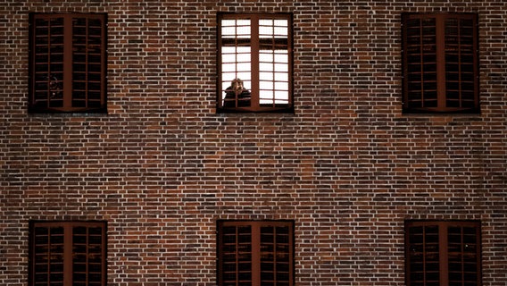 Ein Häftling schaut aus seinem Zellenfenster der Untersuchungshaftanstalt Hamburg (UH) am Holstenglacis. © dpa-Bildfunk Foto: Christian Charisius