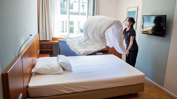 Eine Frau macht in einem Hotelzimmer das Bett. © picture alliance / dpa 