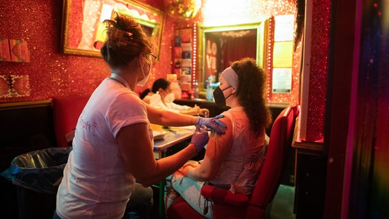 Eine Frau lässt sich in einer Hamburger Bar gegen das Coronavirus impfen.  Foto: Daniel Reinhardt