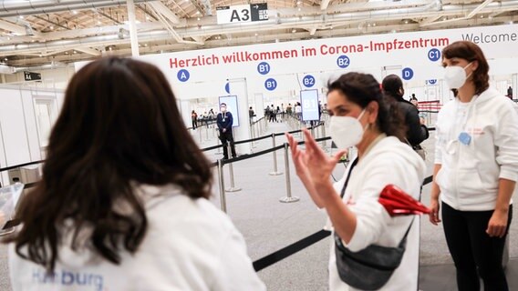 Mitarbeiterinnen unterhalten sich im Eingangsbereich am letzten Öffnungstag im Impfzentrum in den Hamburger Messehallen. © picture alliance / dpa Foto: Christian Charisius