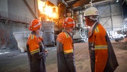 Drei Männer stehen vor einem Elektrolichtbogenofen im Stahlwerk der ArcelorMittal GmbH. © picture alliance/dpa | Jonas Walzberg Foto: Jonas Walzberg