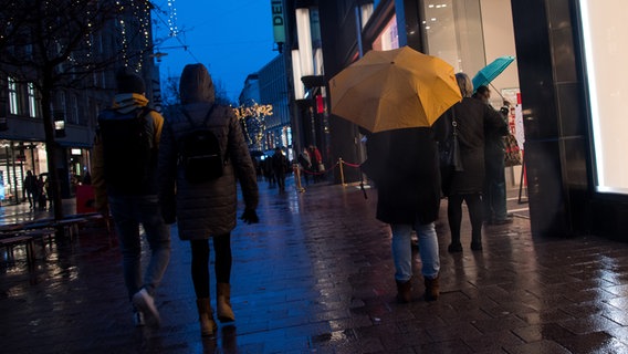 Passanten mit Regenschirmen gehen am verkaufsoffenen Sonntag durch die Hamburger Innenstadt. © dpa Foto: Daniel Bockwoldt