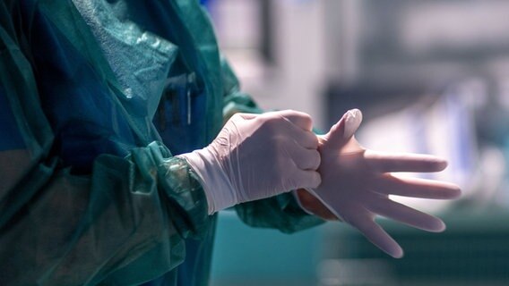 Eine Krankenpflegerin der Intensivstation legt ihre Schutzkleidung an. © dpa Foto: Jens Büttner